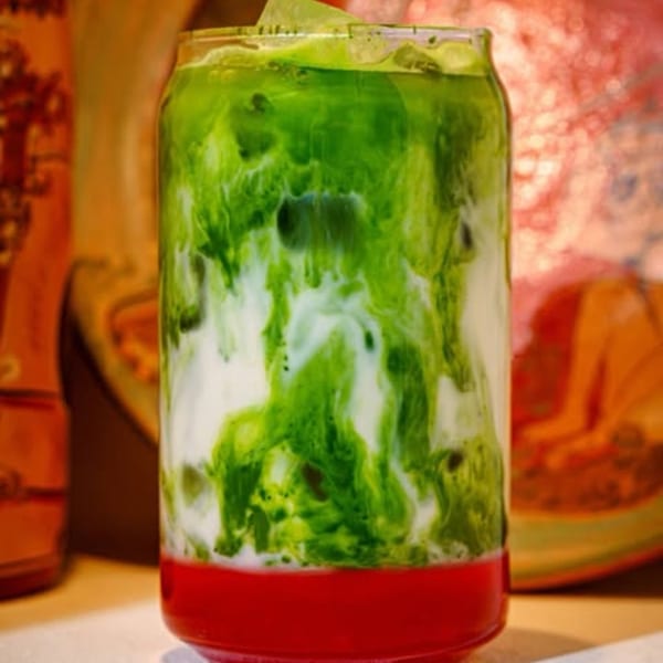 A vibrant layered drink with red at the bottom, white in the middle, and green on top.