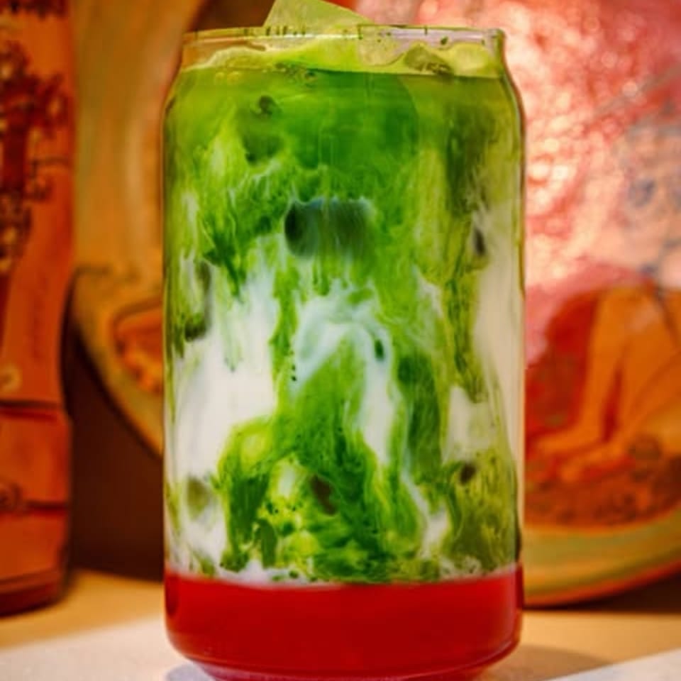 A vibrant layered drink with red at the bottom, white in the middle, and green on top.
